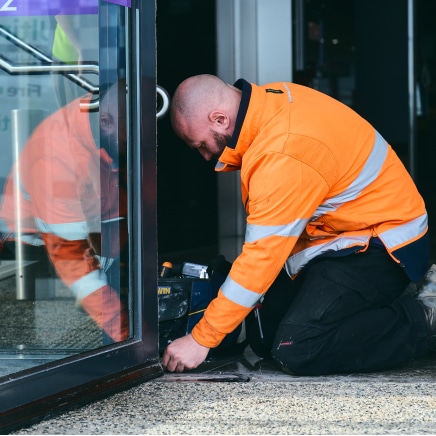 man in orange safety jacket repairing a door
