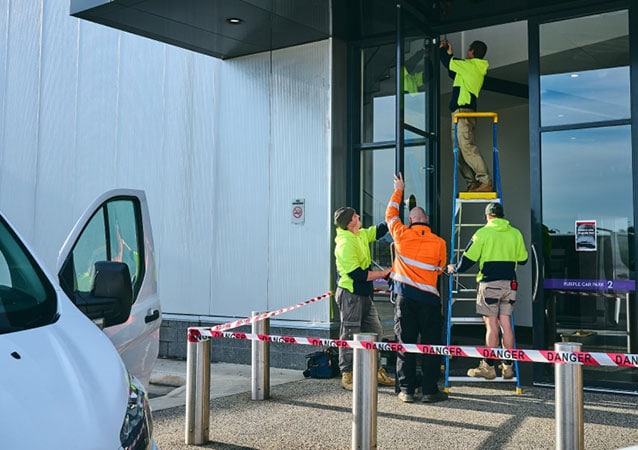 technicians repairing a store front door