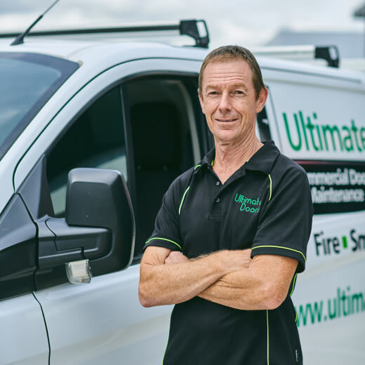 a male Ultimate Doors technician standing next to a service van