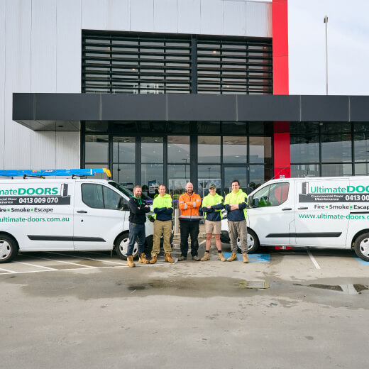 five male Ultimate Doors employees in front of two service vans