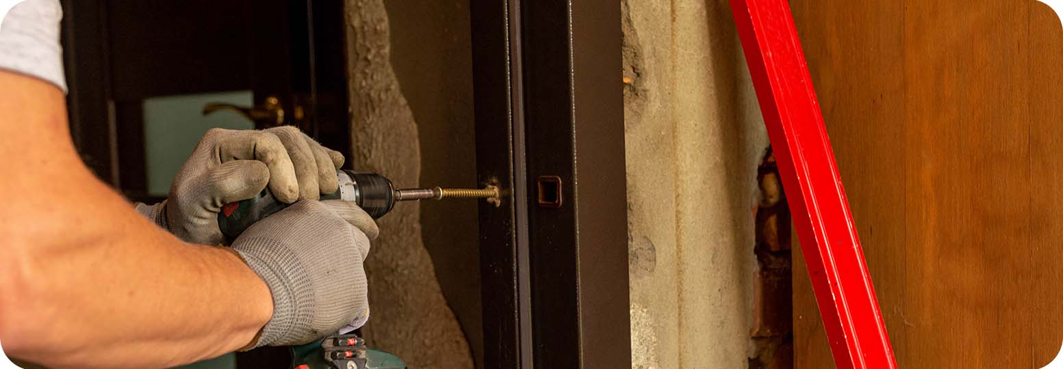 a worker using a power tool to install a door jamb